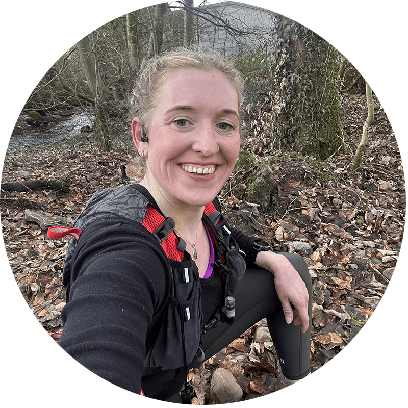 Cat, smiling and resting on a wooded UK trail after a run, ready to discuss personalised online running coaching.